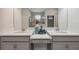 Bright bathroom featuring dual vanities, gray cabinetry, stone countertops, and a large mirror at 17537 Brighton Lake Rd, Land O Lakes, FL 34638