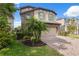 Two-story home showcasing a well-manicured lawn, tropical foliage, and a paver driveway leading to a two-car garage at 17537 Brighton Lake Rd, Land O Lakes, FL 34638