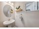 Simple half bathroom with a pedestal sink, round mirror, shelf, and window at 17537 Brighton Lake Rd, Land O Lakes, FL 34638