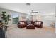 Living room with a leather sofa, ceiling fan, and large windows overlooking the backyard at 17537 Brighton Lake Rd, Land O Lakes, FL 34638