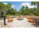 Inviting fire pit area with orange Adirondack chairs, set on a stone paver patio, perfect for outdoor entertaining at 18172 Ramble On Way, Land O Lakes, FL 34638