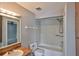Bathroom with wood vanity, full tub and shower, and gray tile at 1883 Clearbrooke Dr, Clearwater, FL 33760