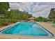 Community swimming pool with clear blue water, surrounded by lush landscaping and lounge chairs at 1883 Clearbrooke Dr, Clearwater, FL 33760