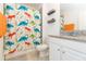 A full bathroom featuring a granite-topped vanity and a whimsical dinosaur-themed shower curtain at 19032 Malinche Loop, Spring Hill, FL 34610