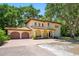 Charming Mediterranean-style home with a two-car garage and a brick driveway, set amidst mature trees at 1966 Freedom Dr, Clearwater, FL 33755