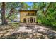 Stunning two-story home with a lovely outdoor patio space and manicured lawn surrounded by mature trees at 1966 Freedom Dr, Clearwater, FL 33755