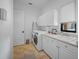 All-white laundry room with modern washer and dryer, sink, and ample cabinet space for storage at 1966 Freedom Dr, Clearwater, FL 33755