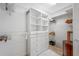 Bright walk-in closet with white shelving, drawers, hanging racks, and a beautiful wooden cabinet at 1966 Freedom Dr, Clearwater, FL 33755