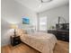 Cozy bedroom featuring wood floors, an accent painting, lamps, and dark wood nightstands at 19808 Sunsplash Ln, Lutz, FL 33558