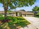 Charming single-story home features a well-manicured lawn, mature trees, and a three-car garage at 19808 Sunsplash Ln, Lutz, FL 33558