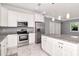 Spacious kitchen boasts stainless steel appliances, a center island, white cabinetry, and pendant lighting, creating a modern style at 212 W Floribraska Ave, Tampa, FL 33603