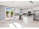 Bright kitchen with granite countertops, white cabinets, an island, and stainless steel appliances leading to patio doors at 212 W Floribraska Ave, Tampa, FL 33603