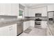 Bright and open kitchen showcasing stainless steel appliances, white cabinets, granite countertops, and tile flooring at 212 W Floribraska Ave, Tampa, FL 33603