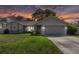 Charming single-story home featuring a well-maintained lawn and attached two-car garage with a beautiful sunset sky at 3074 Dothan Ave, Spring Hill, FL 34609