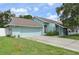 Front exterior of the home featuring a two-car garage, well maintained lawn and landscaping, and light blue paint at 3093 Woodpine Cir, Sarasota, FL 34231