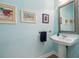 Elegant powder room with a pedestal sink, decorative mirror, wood floors, and light blue painted walls with framed art at 316 5Th N Ave, Safety Harbor, FL 34695