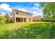 Large backyard with well-maintained lawn, covered patio, and view of neighboring houses at 32718 Summerglade Dr, Wesley Chapel, FL 33545