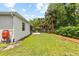 View of the backyard featuring lush green grass, mature trees, and partial shade at 3605 W Paxton Ave, Tampa, FL 33611