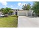 Charming single story home featuring a well-manicured lawn, a two car garage, and tropical landscaping at 3605 W Paxton Ave, Tampa, FL 33611