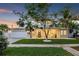Beautiful two-story home featuring a well-manicured lawn, covered porch, and inviting curb appeal at dusk at 3711 W Barcelona St, Tampa, FL 33629