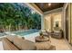 A luxurious covered patio offers comfortable seating, a pool view, and serene tropical landscaping, perfect for outdoor relaxation at 3711 W Barcelona St, Tampa, FL 33629