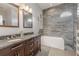 Modern bathroom with a double vanity, soaking tub, and stone accent wall at 4951 Musselshell Dr, New Port Richey, FL 34655