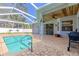 Outdoor pool patio area with brick pavers, a screened enclosure, and a covered section with a ceiling fan at 4951 Musselshell Dr, New Port Richey, FL 34655