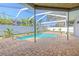 Inviting screened-in pool area featuring a brick patio, tropical plants and clear blue water at 4951 Musselshell Dr, New Port Richey, FL 34655
