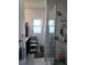 Tiled bathroom featuring a glass-enclosed shower, bright window, and storage shelving unit at 5816 Liverpool Dr, Tampa, FL 33615