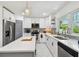 A kitchen featuring white cabinets, stainless steel appliances, a gray island, and a view out the window at 5816 Liverpool Dr, Tampa, FL 33615