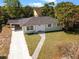 Inviting single-story home with a lush front lawn, gravel driveway, and a convenient carport at 660 Palm Ave, Tarpon Springs, FL 34689