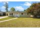 Charming single-story home with a well-maintained lawn, a walkway to the front door, and mature trees on a sunny day at 660 Palm Ave, Tarpon Springs, FL 34689