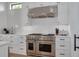 Close-up of the modern kitchen with Wolf range, stainless hood, white subway tile, and cabinetry at 721 Brightwaters Ne Blvd, St Petersburg, FL 33704