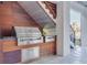 This outdoor grill features stainless steel appliances and custom wood finish underneath the outdoor staircase at 721 Brightwaters Ne Blvd, St Petersburg, FL 33704