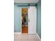 A view of a closet with a white sliding barn door and black hardware, showcasing clothing racks and shelving at 7645 Sun Island S Dr # 207, South Pasadena, FL 33707