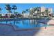Community pool with a view of nearby condos, surrounded by lounge chairs and palm trees at 7645 Sun Island S Dr # 207, South Pasadena, FL 33707