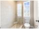 Modern shower with glass enclosure, neutral tile, and updated fixtures, next to toilet and window at 916 Hemingway Cir, Tampa, FL 33602