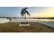 Outdoor seating with a scenic lake view and a tall palm tree at sunset, framed by a white picket fence at 9416 Star Gazer Ln, Riverview, FL 33578