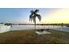 Waterfront view with palm trees, white picket fence and fire pit creates a serene outdoor space for relaxation at 9416 Star Gazer Ln, Riverview, FL 33578