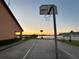 Enjoy the community basketball court with waterfront views at sunset, surrounded by lush greenery and a charming picket fence at 9416 Star Gazer Ln, Riverview, FL 33578