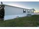 Exterior view of a manufactured home featuring light siding, a green lawn, and a neatly maintained landscape at 9416 Star Gazer Ln, Riverview, FL 33578