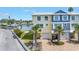 Aerial view of a two-story townhome with a well-kept lawn, paved driveway, palm trees, and waterfront access at 100 Windrush Blvd # 1, Indian Rocks Beach, FL 33785