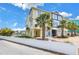 Exterior view of a two-story townhome with a manicured lawn, white fence, and beautiful palm trees adding tropical charm at 100 Windrush Blvd # 1, Indian Rocks Beach, FL 33785