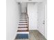 Elegant staircase with wooden treads and white risers, complemented by stylish gray tile flooring at 100 Windrush Blvd # 1, Indian Rocks Beach, FL 33785