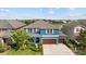Aerial view of blue home with a brown roof, lush landscaping, and a spacious driveway at 10017 Smarty Jones Dr, Ruskin, FL 33573
