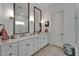 Elegant bathroom featuring double sinks with framed mirrors, white cabinets, and a glass-enclosed shower, exuding luxury at 1025 Seagrape Dr, Ruskin, FL 33570