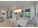 Bright dining room features a modern chandelier, large windows, and stylish white wood furniture at 1025 Seagrape Dr, Ruskin, FL 33570