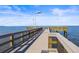 Long wooden dock extending over the calm blue water with clear skies above at 1025 Seagrape Dr, Ruskin, FL 33570