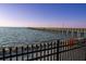 Seaside pier with lights extending over the water, protected by a black fence at 1025 Seagrape Dr, Ruskin, FL 33570