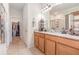 Bathroom with dual sinks, granite countertops, wood cabinets, and a separate glass-enclosed shower at 11938 Bahia Valley Dr, Riverview, FL 33579